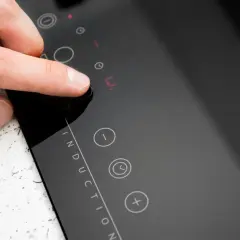 Doigt appuyant sur un bouton de la plaque induction erreur e. L'écran affiche un code d'erreur.