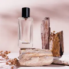 Szklana buteleczka perfum na kamieniach, otoczona suchymi gałązkami. Zapach niczym mocno pudrowe perfumy, delikatny i subtelny.