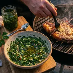 Un steak grillé est badigeonné avec une sauce chimichurri fraîche et vibrante, prête à être dégustée.