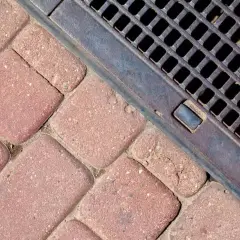 Kostka brukowa i metalowa kratka ściekowa zapewniające sprawne odwodnienie domu.