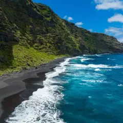 Costa salvaje con arena negra y mar azul intenso, un rincón idílico de las playas de Canarias.