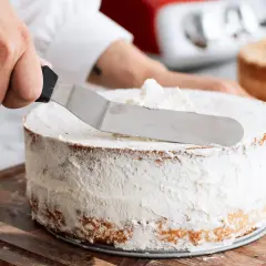 En hand sprider fluffig grädde på en tårta. Ett perfekt tårta recept att följa!