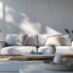 Ein hellgraues Sofa mit Kissen in Grau und Rosé. Die Frage, welche Farbe passt zu grau, wird hier elegant beantwortet: zarte Pastelltöne und Grünpflanzen.
