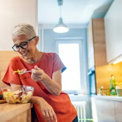 Femme souriante de 50 ans savoure une salade fraîche. Une alimentation saine pour maîtriser les calories.