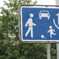 Zeichen 325.1: Fußgängerzone mit spielenden Kindern und Autos. Ein Haus symbolisiert Wohngebiet.