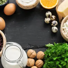 Vielfalt an calcium lebensmittel: Milch, Käse, Joghurt, Eier, Bohnen, Datteln, Nüsse, Orangen und Petersilie.