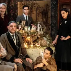 Il cast del film "Natale in casa Cupiello" posa davanti a un presepe illuminato.