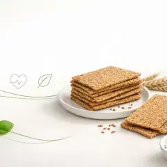 Stos chrupkich wafli ryżowych na talerzyku, obok kłosów zboża i miseczki z twarożkiem. Czy wafle ryżowe są zdrowe? Tak, to świetna baza do zdrowych przekąsek.