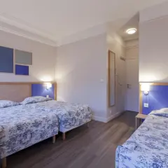 Pokój hotelowy z trzema łóżkami, idealny dla rodziny szukającej odpowiedzi, gdzie najlepiej nocować w Paryżu.