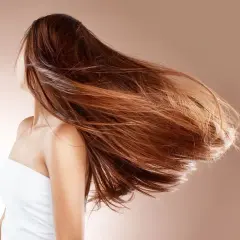Mujer con cabello largo y castaño moviéndose con el viento. ¿Cuánto crece el pelo en un año mujer?