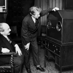 Dwóch mężczyzn przy pierwszym telewizorze. Jeden siedzi, drugi stoi i dotyka obudowy.