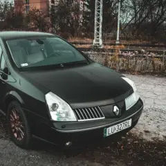Czarny Renault Vel Satis z miedzianymi felgami stoi przy torach kolejowych.