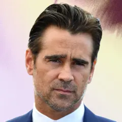 Colin Farrell med slick back-frisyr, bär en blå kostym och vit skjorta.