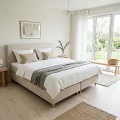 Ein helles Schlafzimmer mit einem **standard Bett**, weißen Bettwäsche, einem Holzbettrahmen und großen Fenstern mit Blick auf einen Garten.