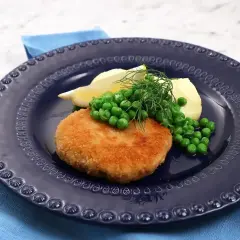 En gyllene havets wallenbergare serveras med potatis, gröna ärtor, citronklyfta och dill på en mörkblå tallrik.