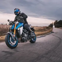 Motocyklista w kasku z brytyjską flagą pokonuje zakręt na drodze, doświadczając zjawiska shimmy.