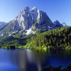 El estany de Sant Maurici, un lago alpino rodeado de bosques de pinos y picos nevados, refleja la majestuosidad de la naturaleza.
