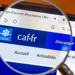 Loupe sur l'écran d'un ordinateur affichant le site caf.fr, page d'accueil des allocataires. L'accès aux informations est facilité.