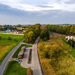 Krajobraz z Gołkowic: domy, droga, ścieżka rowerowa i las.