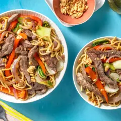 Två skålar med biff med nudlar, paprika, lök och jordnötter. En härlig asiatisk måltid.