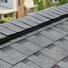 Graues Bitumen-Dach mit Lüftungsgitter. Die Schindeln sind dicht verlegt und bilden eine schützende Schicht.