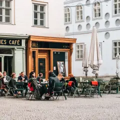 Menschen sitzen vor dem "Kleines Café" und genießen einen kleinen braunen Kaffee.
