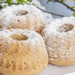 Trzy puszyste muffinki piaskowe posypane cukrem pudrem, gotowe do podania.