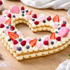 Un magnifique number cake licorne en forme de cœur, garni de fruits rouges, de macarons roses et de crème onctueuse.