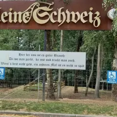 Schild "Kleine Schweiz" in Velbert. Ein Spruch lädt zum Verweilen ein. Parken, essen, trinken – perfekt für eine Wanderung.