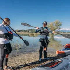 Para szykuje się na spływy kajakowe Podkarpacie. Trzymają wiosła, obok leżą kajaki.