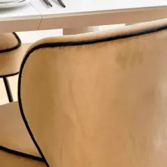 Chaises au revêtement velours couleur camel, bordées d'un passepoil noir, autour d'une table blanche.