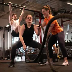Frauen trainieren mit Seilen, ein Mann hängt an einer Klimmzugstange. Ein Blick in die Praxis der Athletiktrainer Ausbildung.