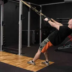Mężczyzna wykonuje podciąganie na TRX, ćwicząc plecy i ramiona.