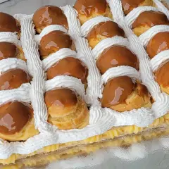 Deliciosa torta rellena de crema pastelera y cubierta con profiteroles bañados en dulce de leche y decorada con crema chantilly.