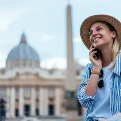 Uśmiechnięta turystka w Rzymie, ciesząca się rozmową przez telefon dzięki internetowi w roamingu.