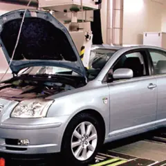 Srebrna Toyota Avensis 2.0 D4D z otwartą maską stoi na stanowisku diagnostycznym.