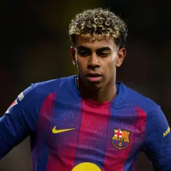 Młody piłkarz Lamine Yamal w koszulce FC Barcelony, z charakterystyczną fryzurą i skupionym spojrzeniem.