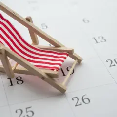 Miniaturowa leżanka plażowa na kalendarzu z zaznaczonymi dniami.