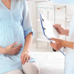 Lekarz spisuje dokumentację medyczną dla ciężarnej kobiety. Dowiedz się, co przysługuje kobiecie w ciąży bez pracy.