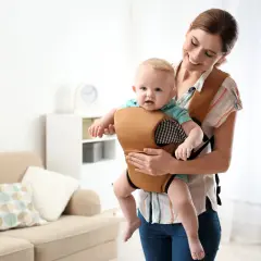 Uśmiechnięta mama trzyma dziecko w wygodnym nosidle. To alternatywa dla chusty, zapewniająca komfort i bezpieczeństwo.
