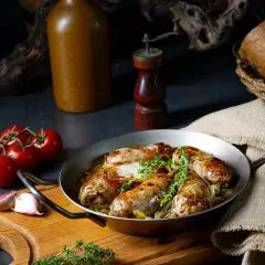 Soczysta biała kiełbasa pieczona w piwie, podana z ziołami, pomidorami i czosnkiem. Idealna na obiad.