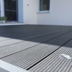 Moderne WPC Terrasse Ideen: Dunkelgraue Dielen mit integrierter Beleuchtung schaffen ein stilvolles Ambiente.