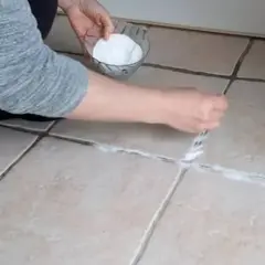 Application d'une pâte de bicarbonate et vinaigre pour nettoyer joint salle de bain.