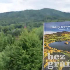 Książka "Góry Opawskie" na tle zielonych wzgórz. Okładka przedstawia malowniczy krajobraz z jeziorem i jesiennymi barwami.