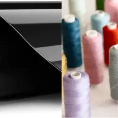 Rouleau de vinyle noir brillant pour flocage textile, à côté de bobines de fil colorées.