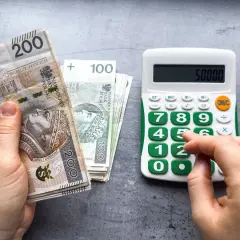 Dłoń trzyma banknoty 200 zł i 100 zł, obok kalkulator z wyświetloną kwotą 50000. Czy to najniższa brutto?