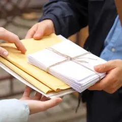 Listonosz przekazuje koperty. Zastanawiasz się, ile zarabia listonosz za taką pracę?