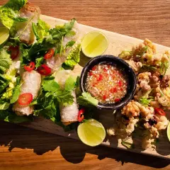 Krispiga cha gio med färska örter, lime och en dippsås. Bredvid ligger friterad bläckfisk.