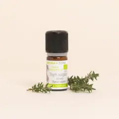 Flacon d'huile essentielle de thym vulgaire, aux notes aromatiques et purifiantes, posé à côté de brins de thym frais.