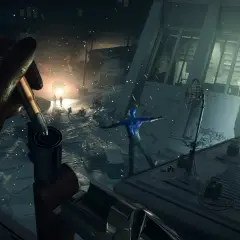Ręka w rękawiczce ładuje broń, celując w niebieską postać na dachu. Scena z gry Deathloop, idealna do poradnika.